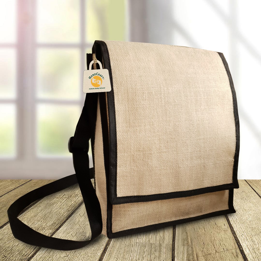 Flap-front sling bag with dark trim and a long strap, photographed on a surface.